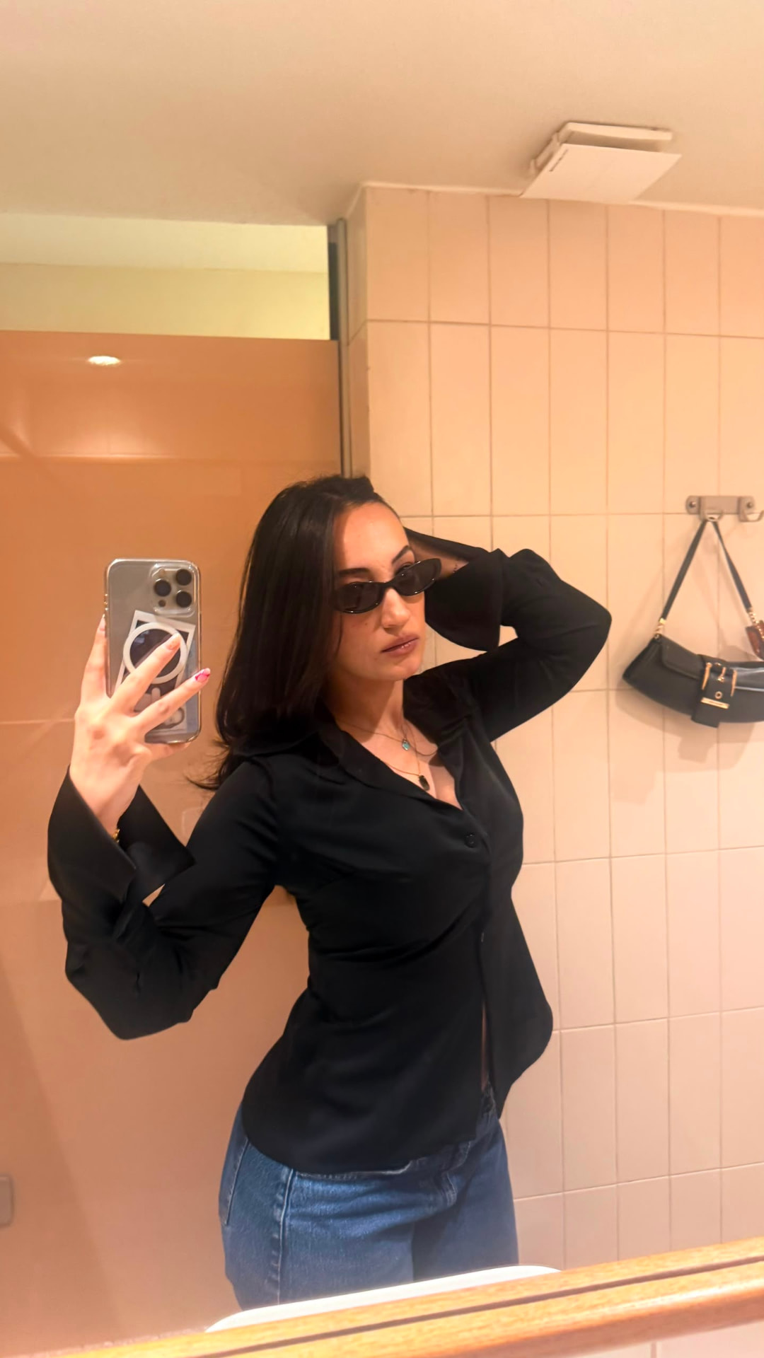 Mirror photograph of a person wearing a fitted black shirt and jeans